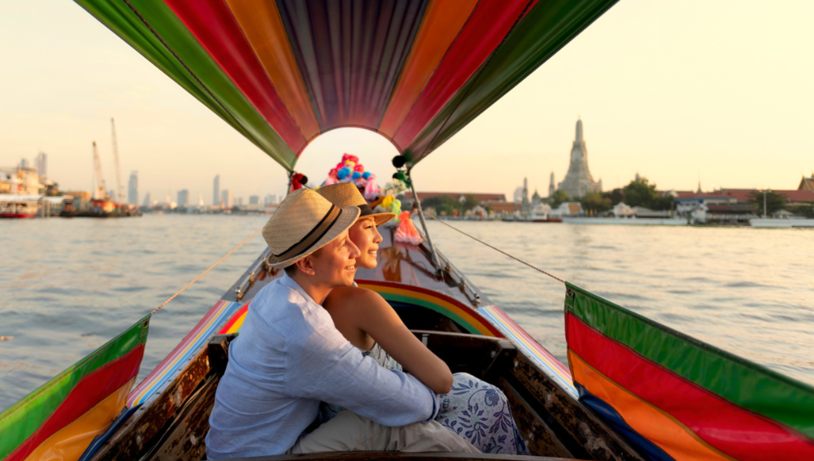 Couple sitting in boat together on water as they hold each other during sunset