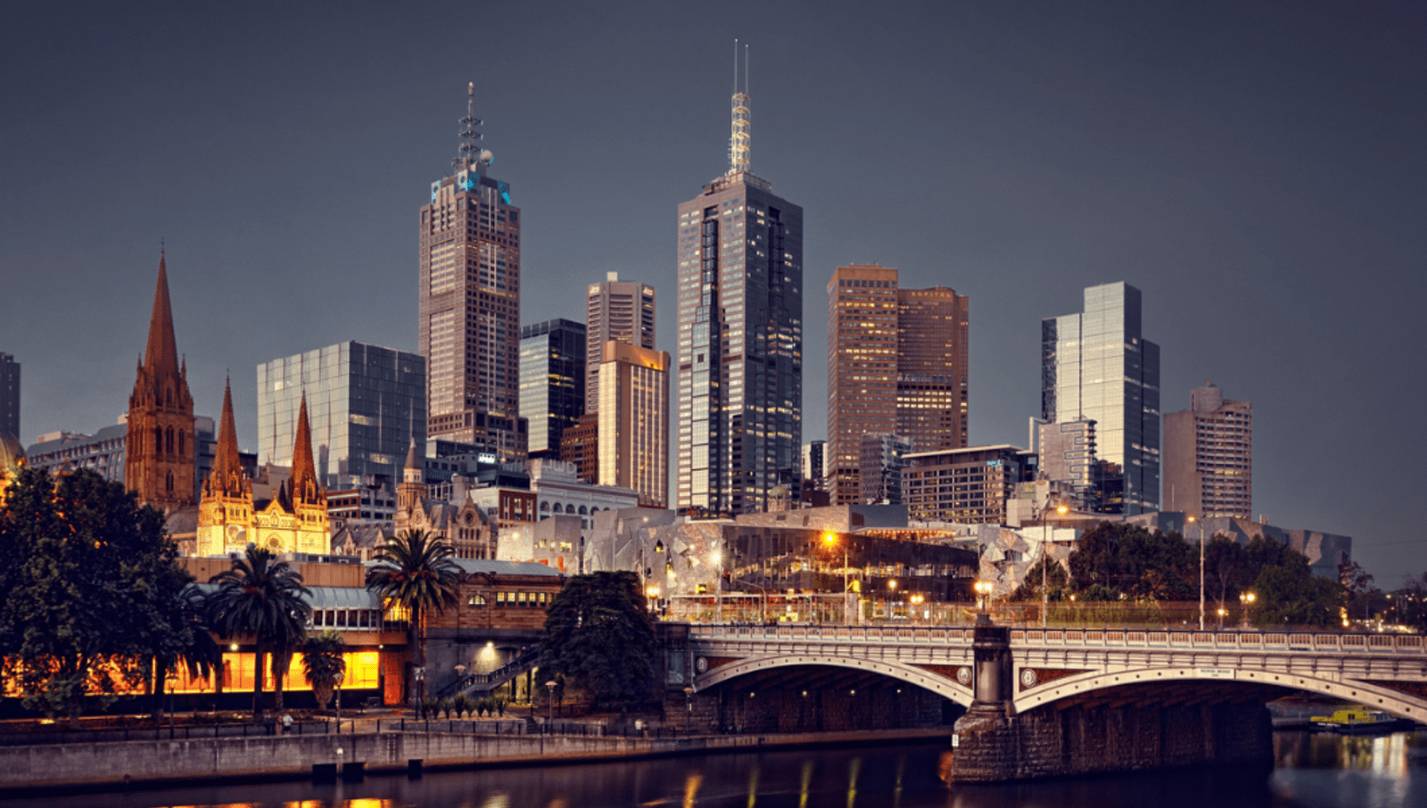 bridge over river in front of melbourne city at night