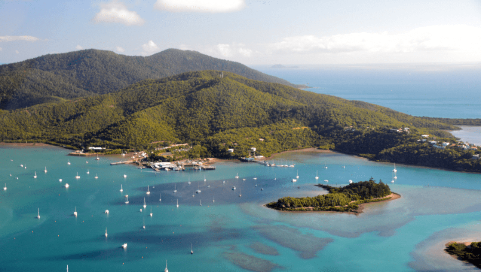 Mountain by the ocean with lost of boats floating on water