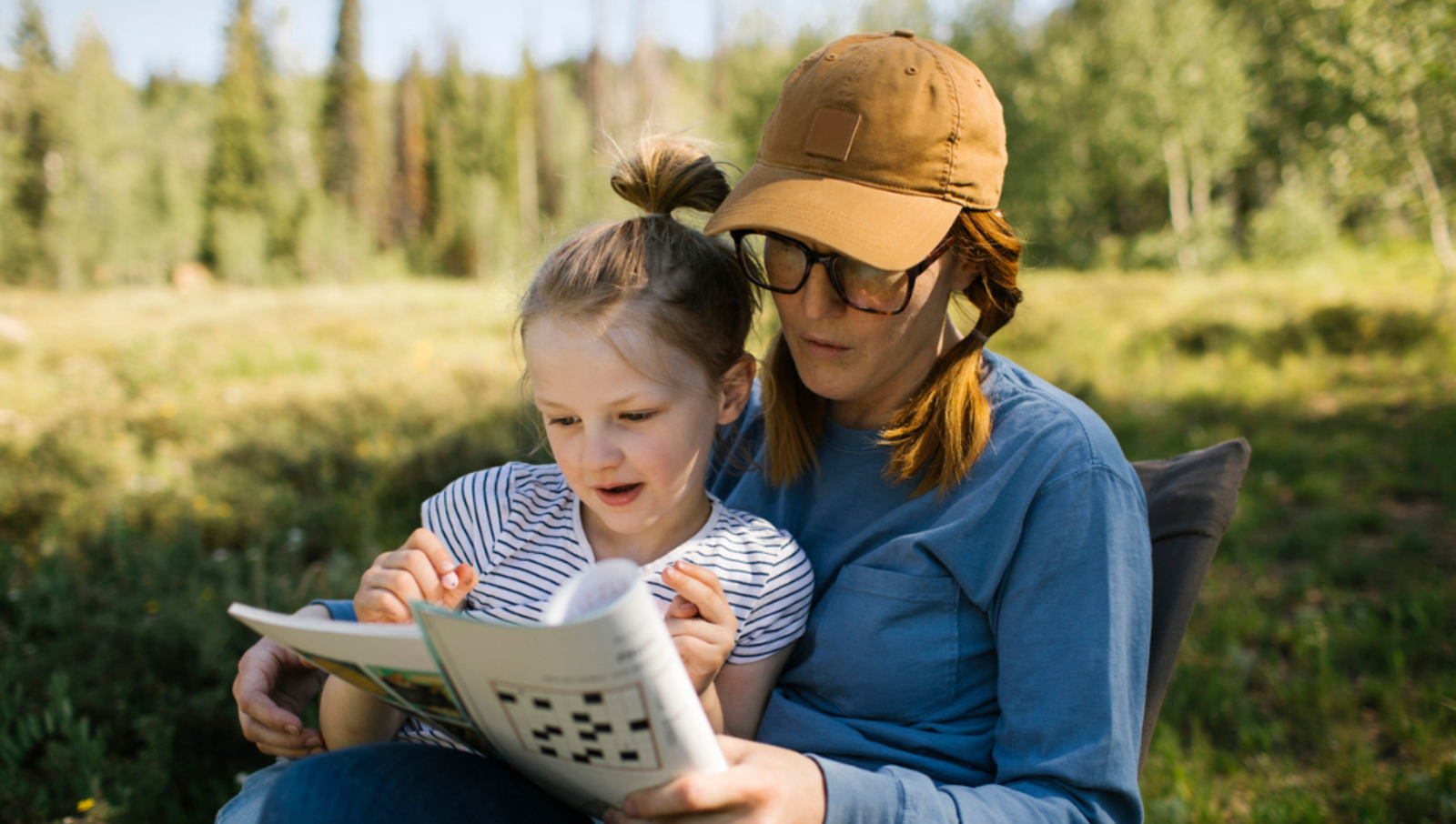 Mum holding book full of brain puzzles while daughter leans on her and looks at the book