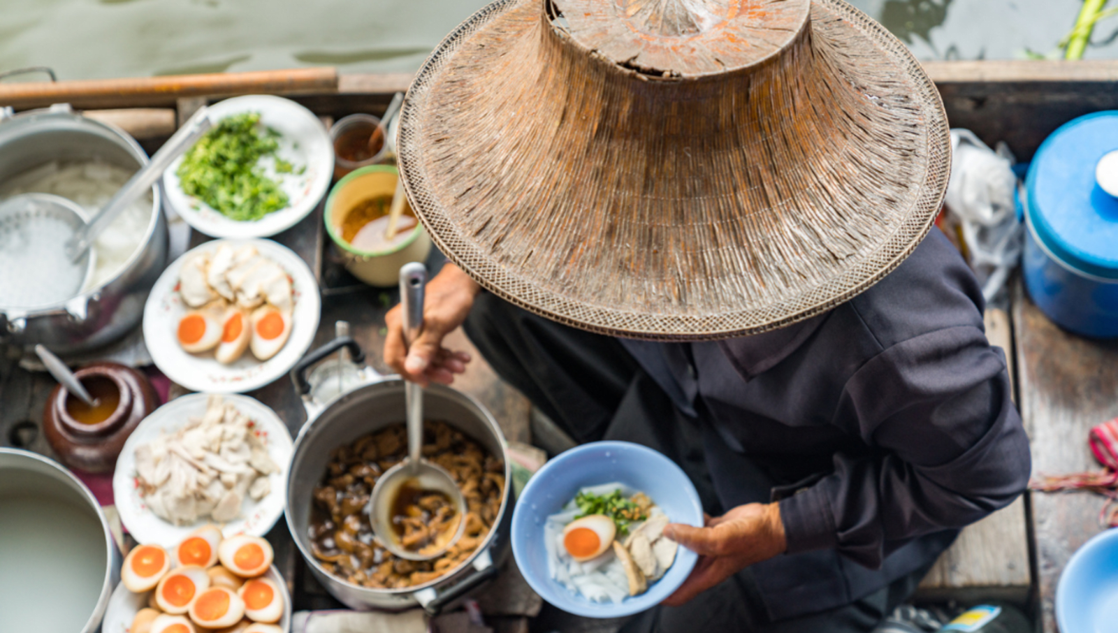 lady in boat with food spooning soup into bowl