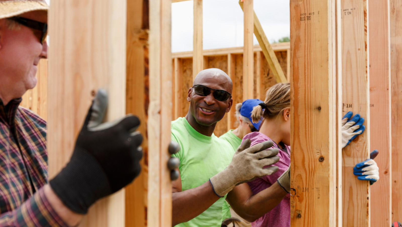 volunteers holding up panels of wood while wearing gloves