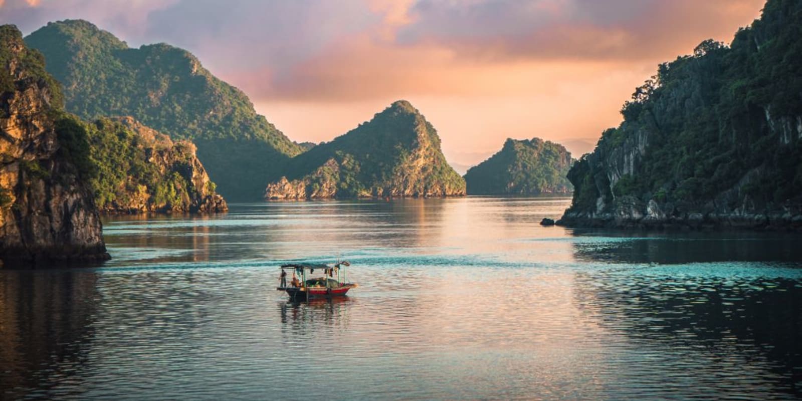 A small fishing boat floating on a lake with stunning mountain scenery in the background