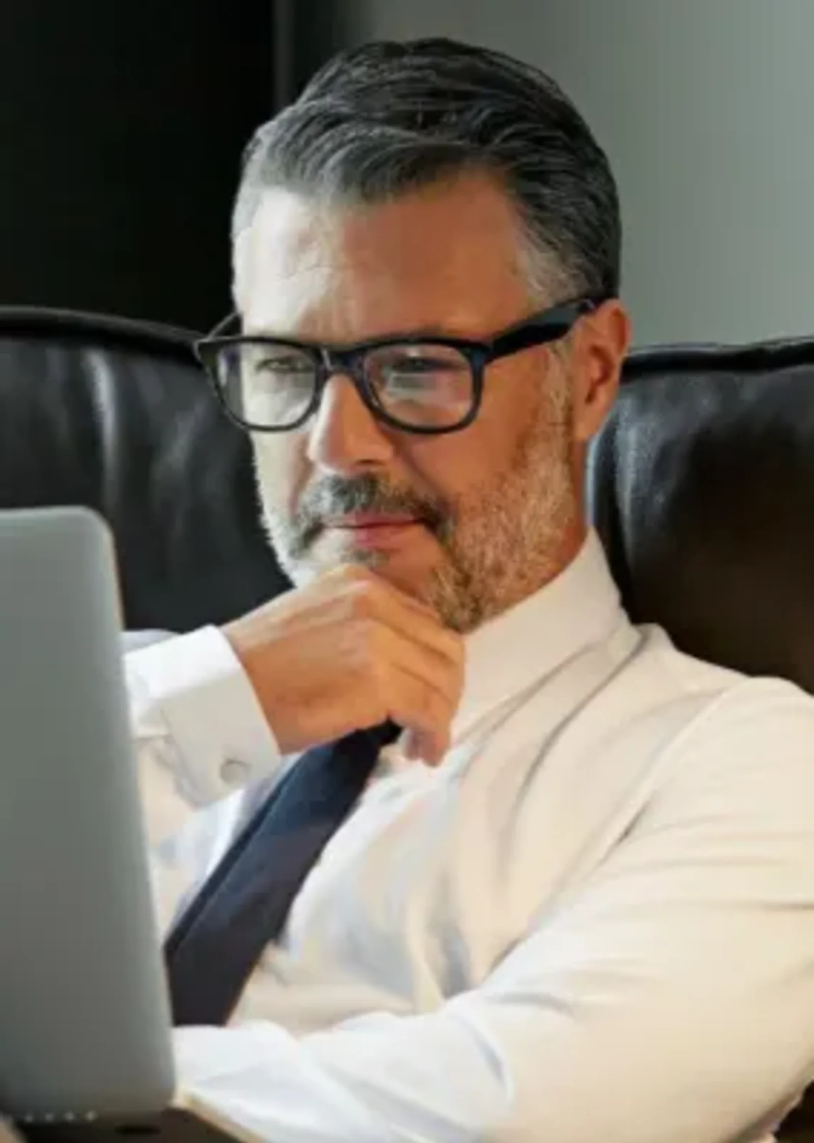 Elderly man smiling while looking at a laptop