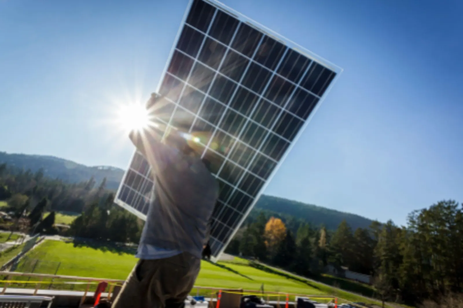 a builder is holding a solar panel under the strong sun light