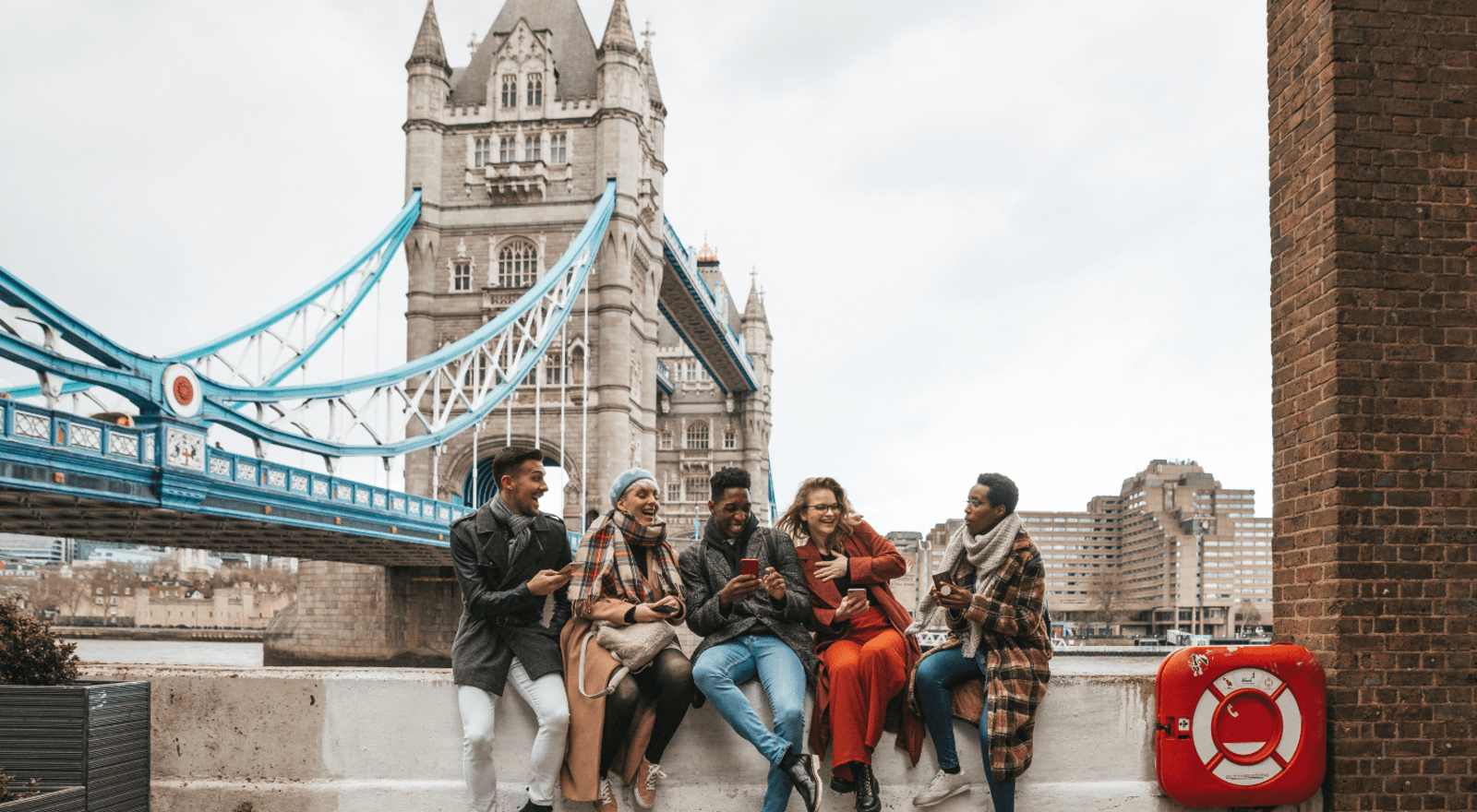 group of friends sitting on ledge by bridge
