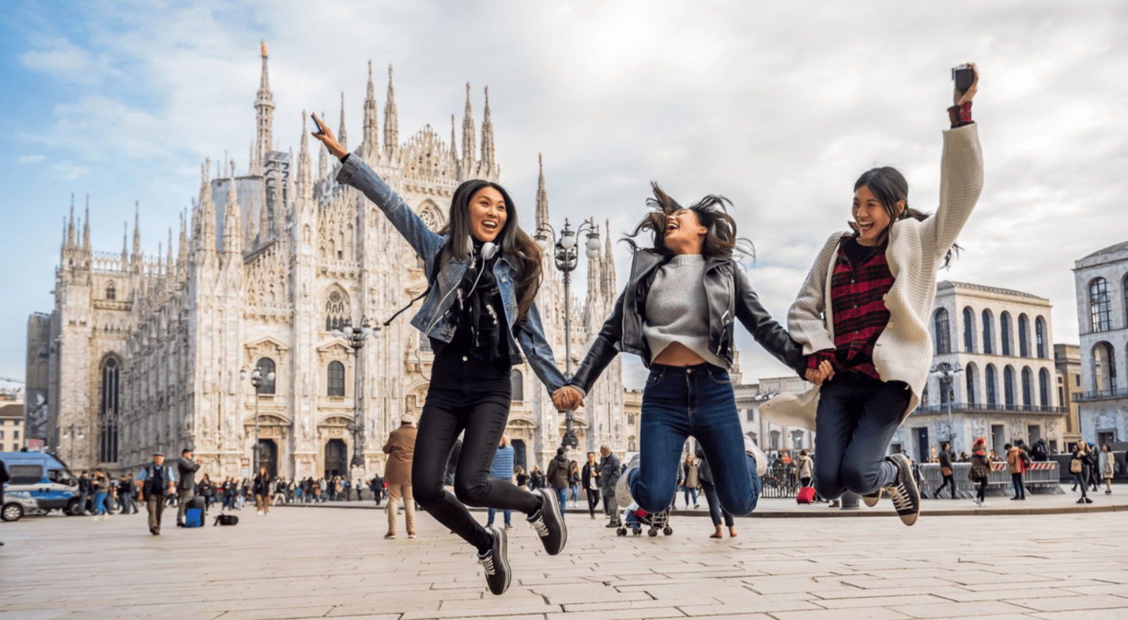 Three young women jumping in air in front of cathedral
