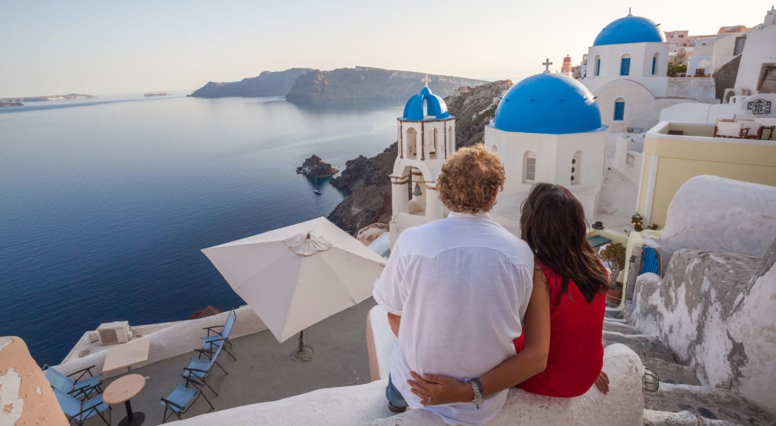 couple sitting on ledge in santorini