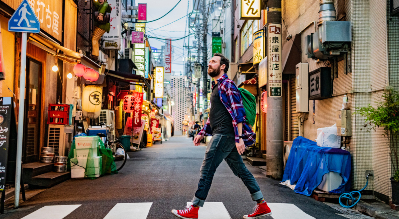 man walking past alley way in Japan on zebra crossing wearing red converse 