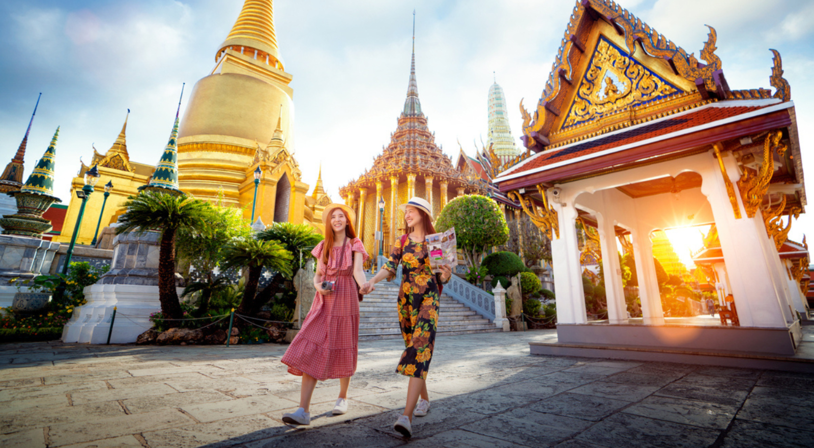 two women holding hands and walking in front of temple