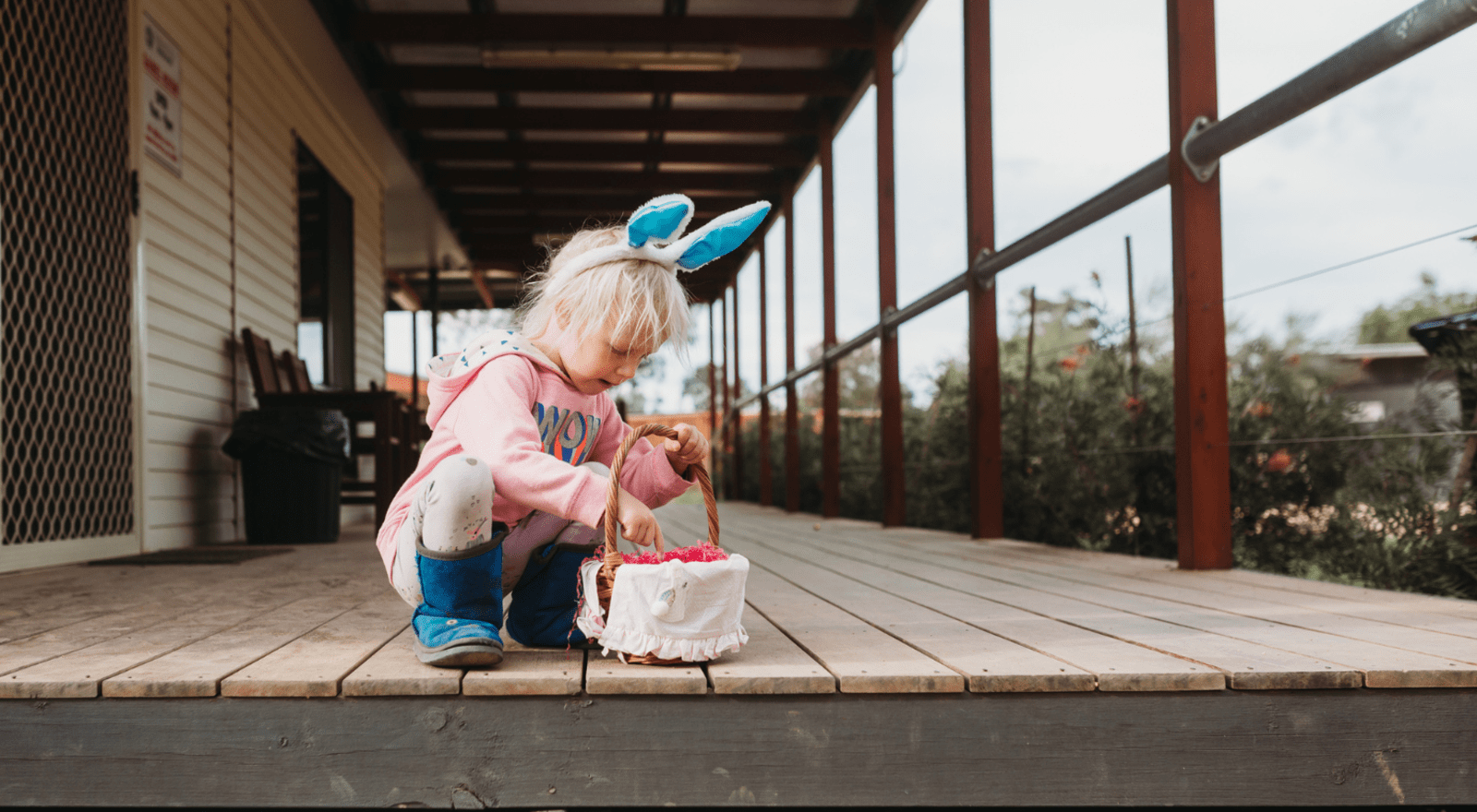 child with rabbit ears putting eggs in basket easter