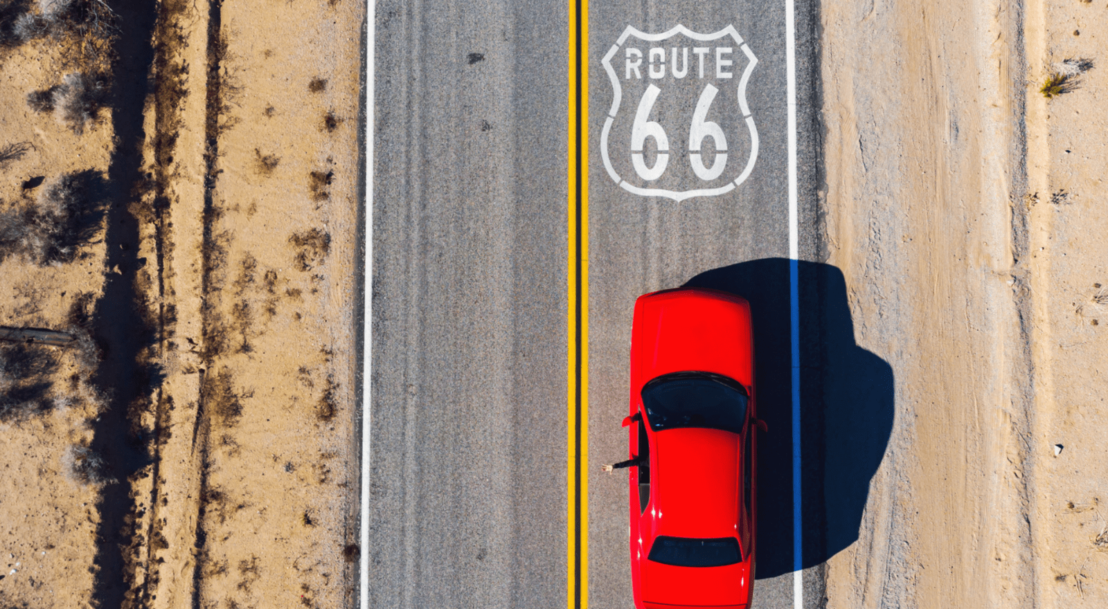 red car driving along route 66 with arm out of window