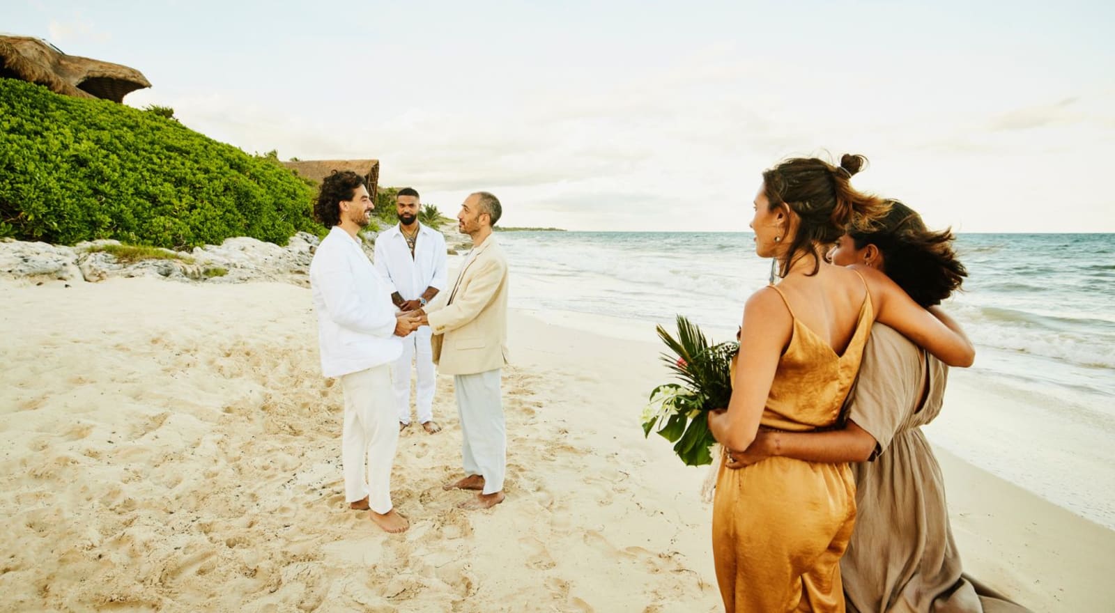 couple getting married on beach with to people watching
