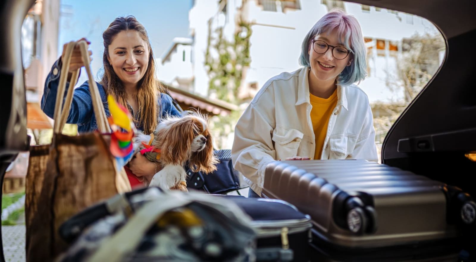 couple packing suitcases into back of car