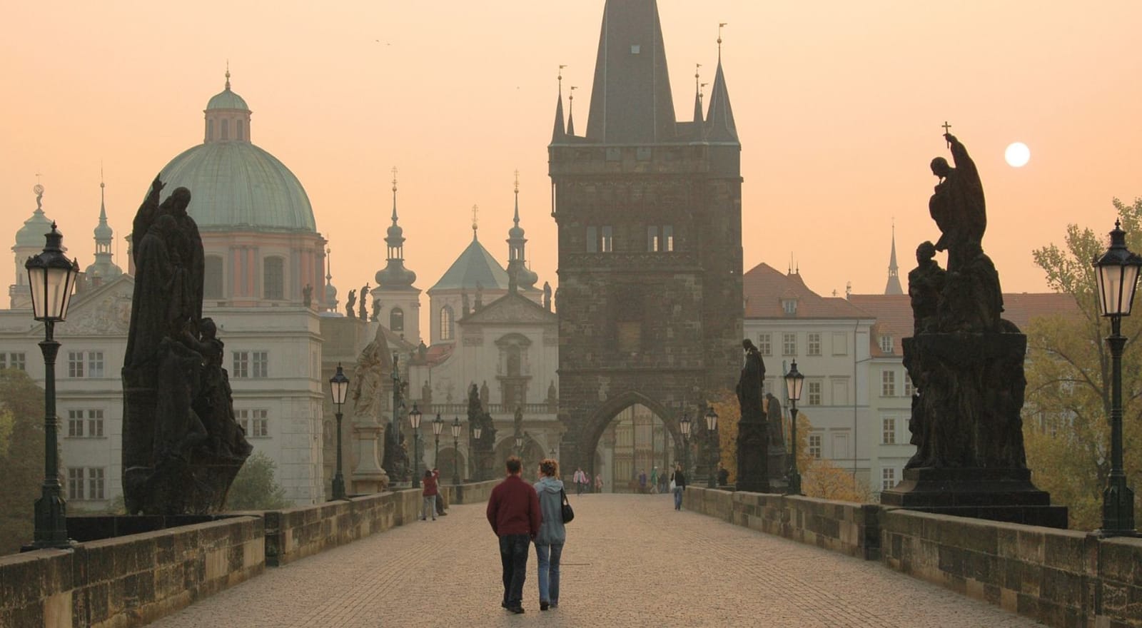 couple walking across bridge in prague