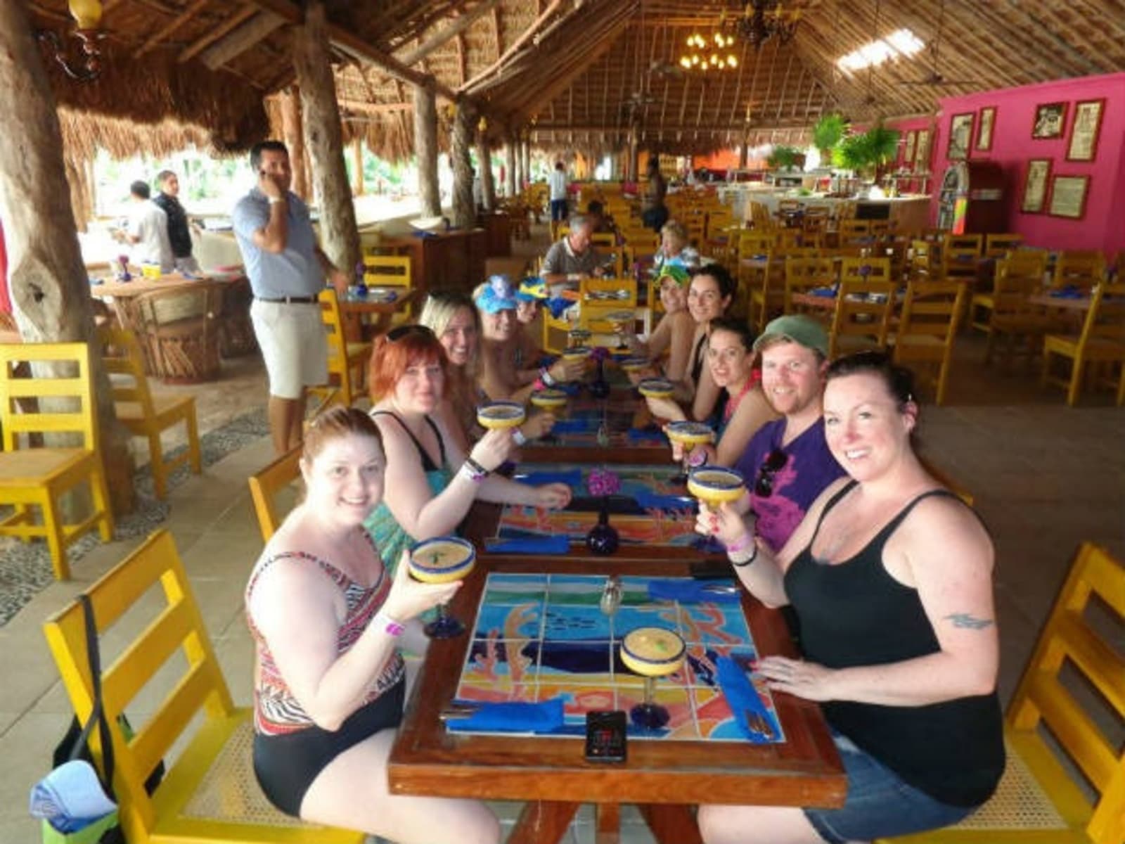 Group of friends drinking margaritas in an open bar with a thatched roof