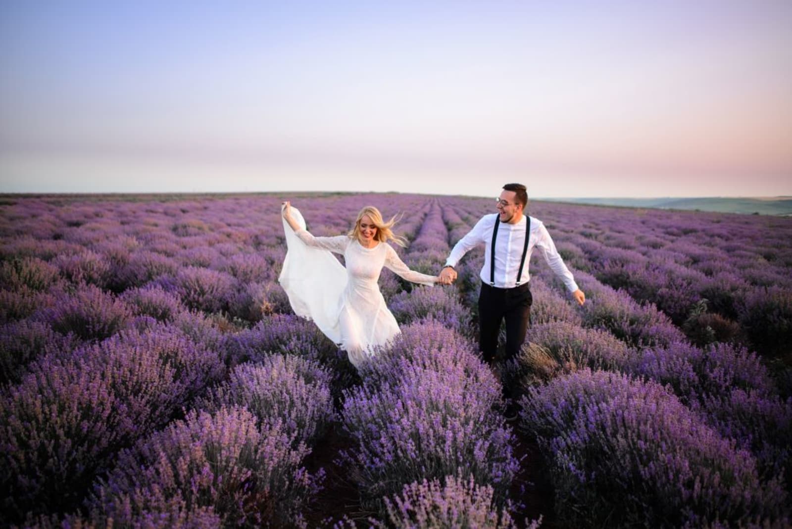 Wedding couple walking through lavender field in Provence, France