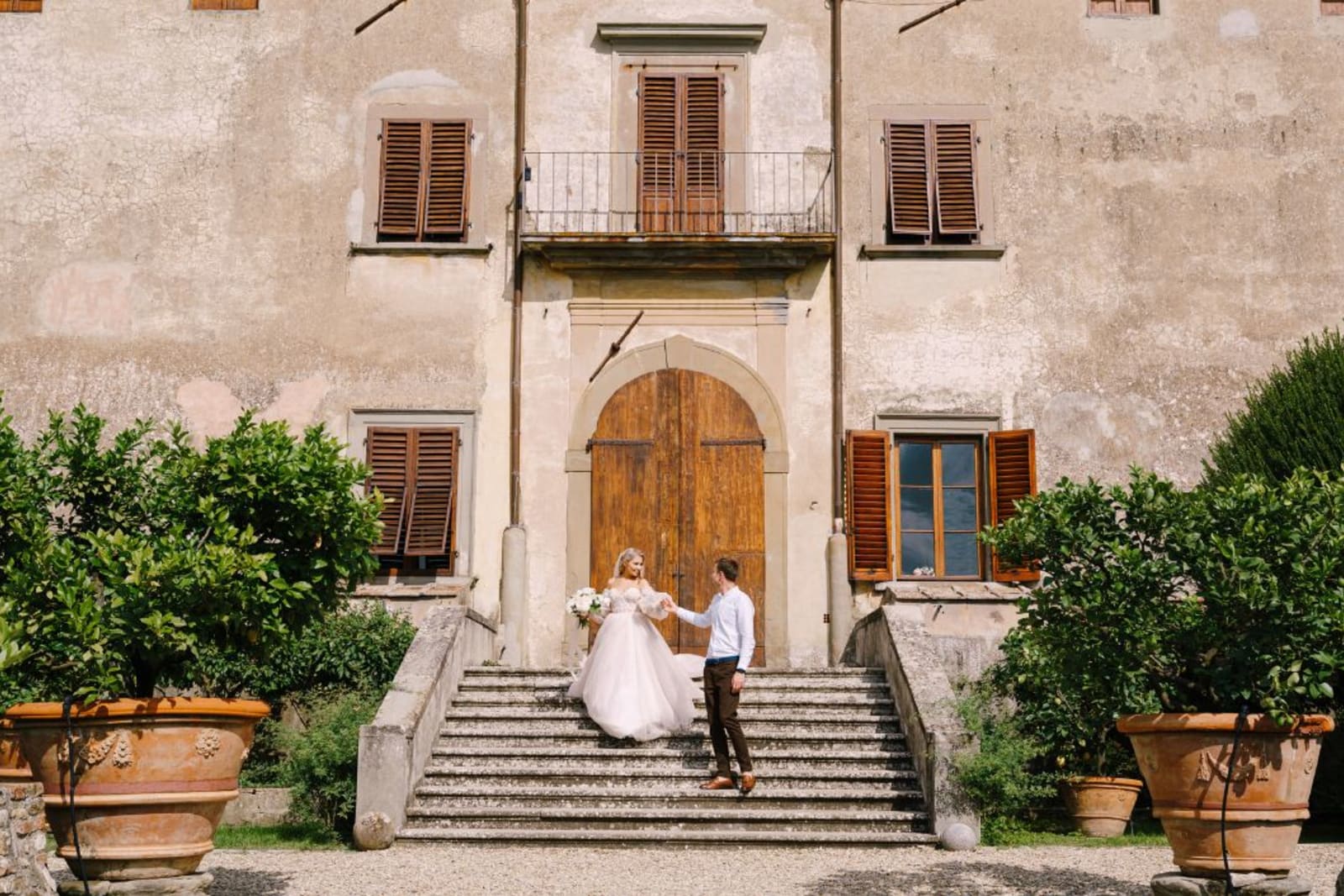 Wedding couple on the steps of a villa in Tuscany