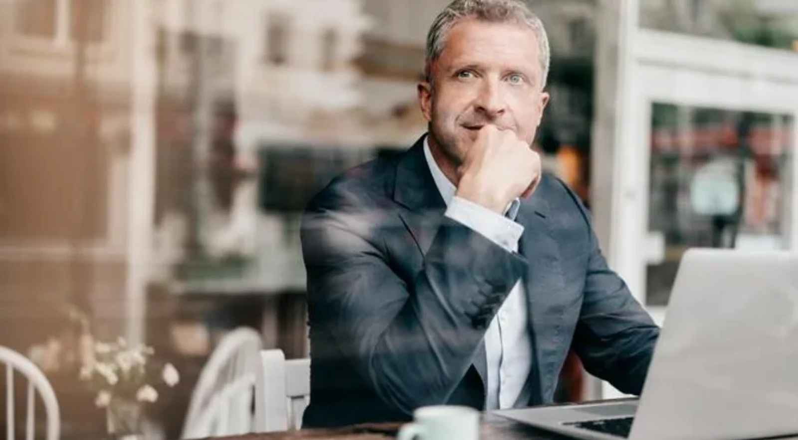 man looking out window using laptop