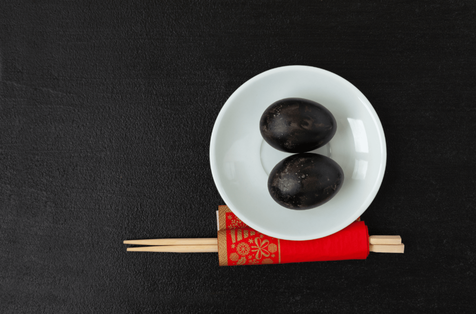 Japan Hakone black eggs served on a white plate with chopsticks beside them.