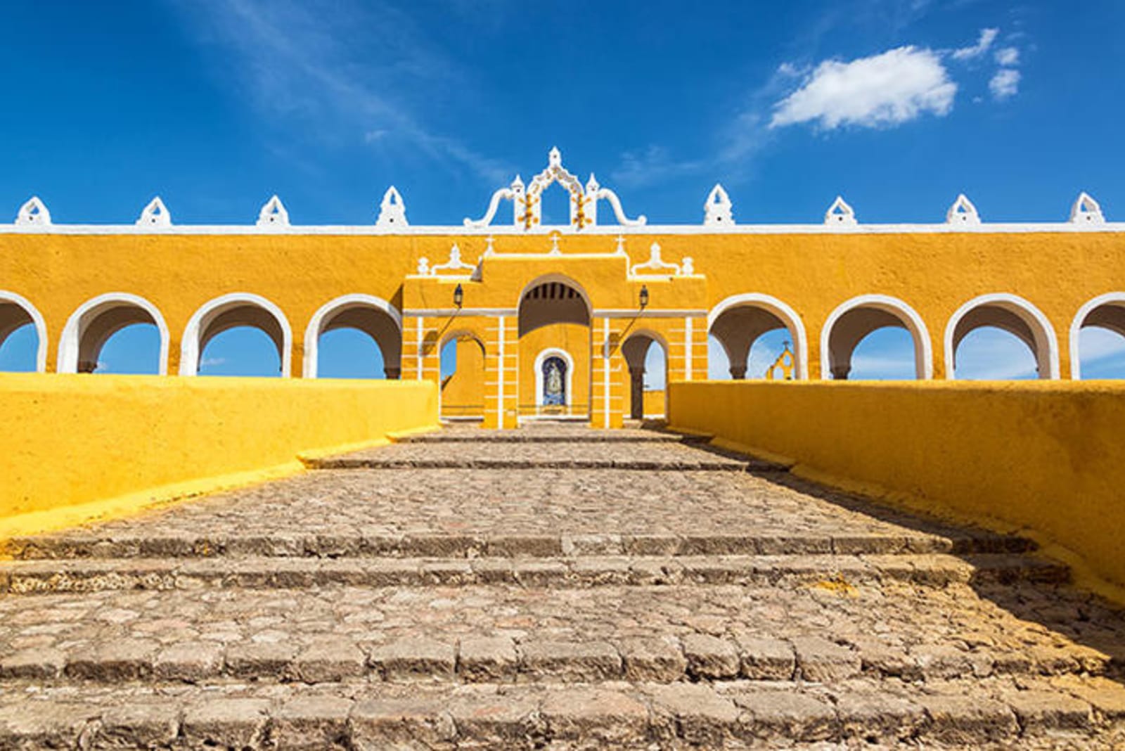 Izamel - Bright yellow building with white-lined arches and a cobblestone stairway