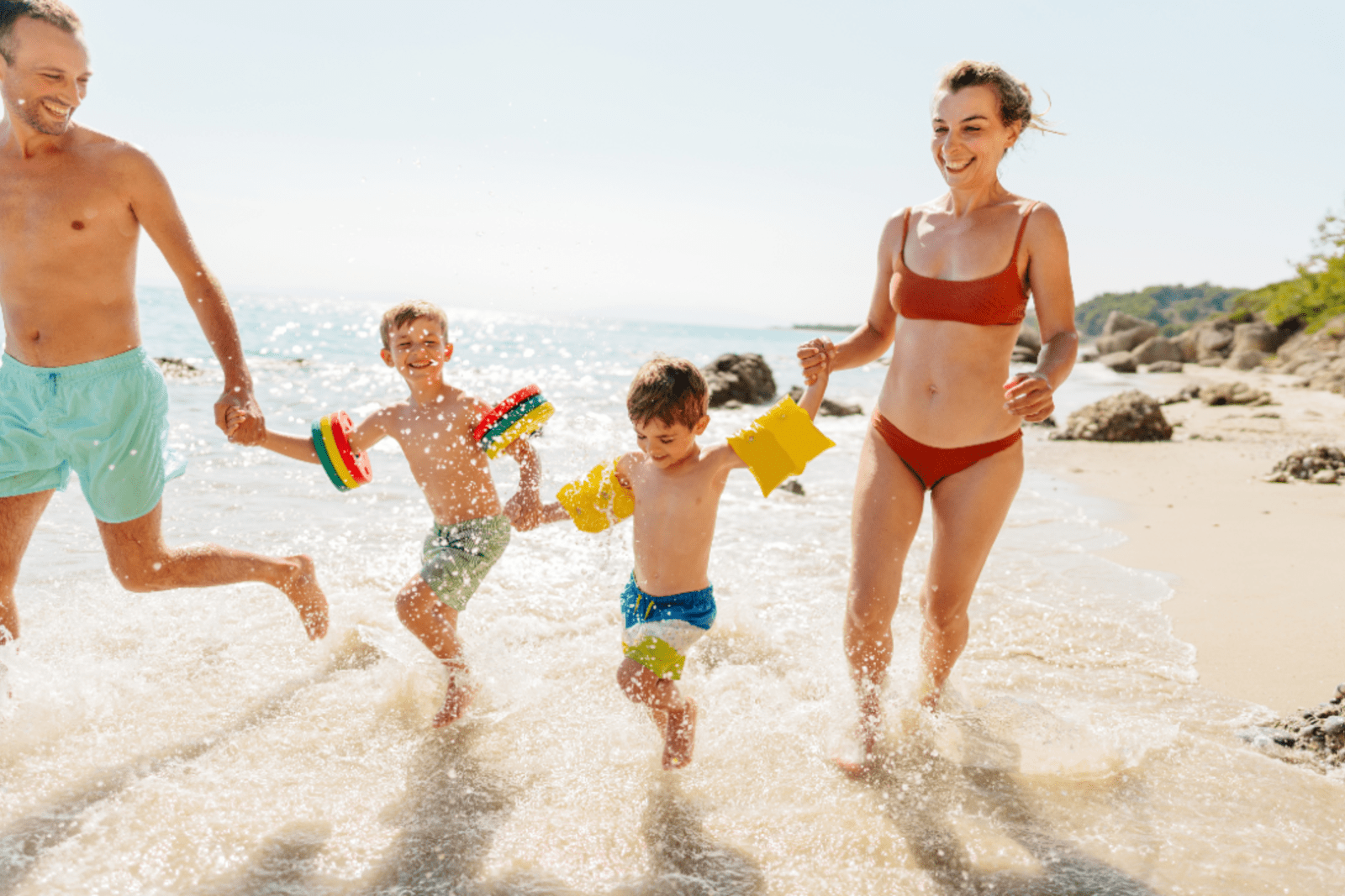 Parents with their two young boys running on a beach in the Caribbean