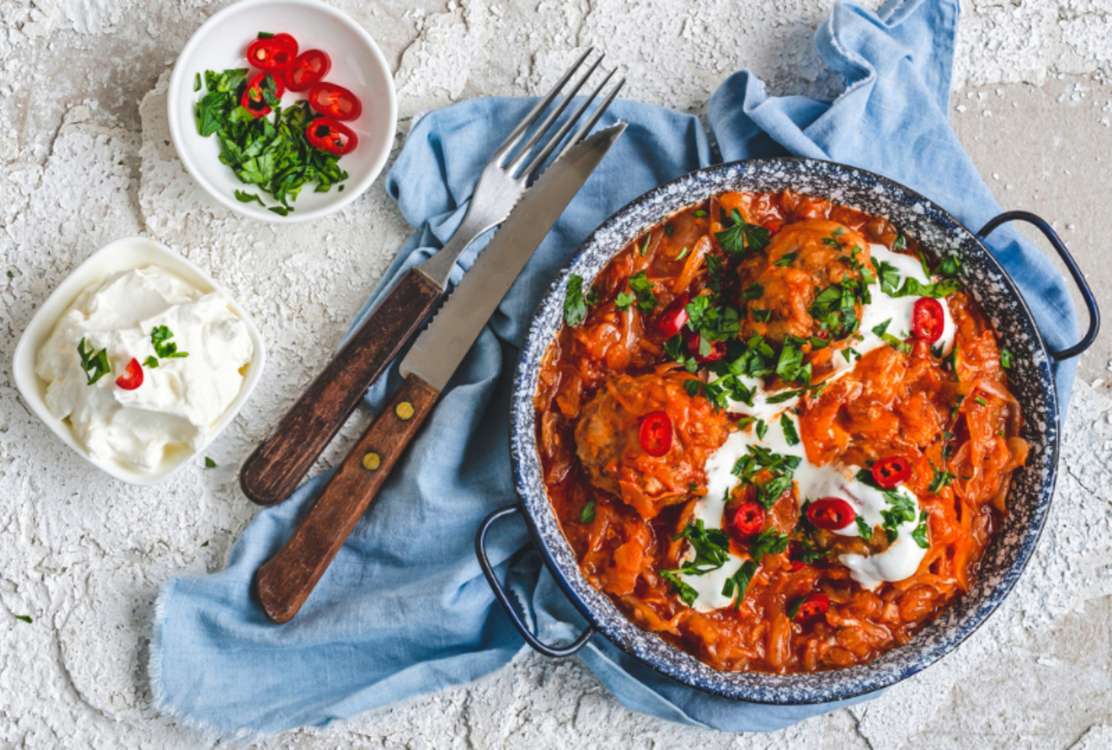 one large bowl of food and two smaller bowls with a knife and fork 