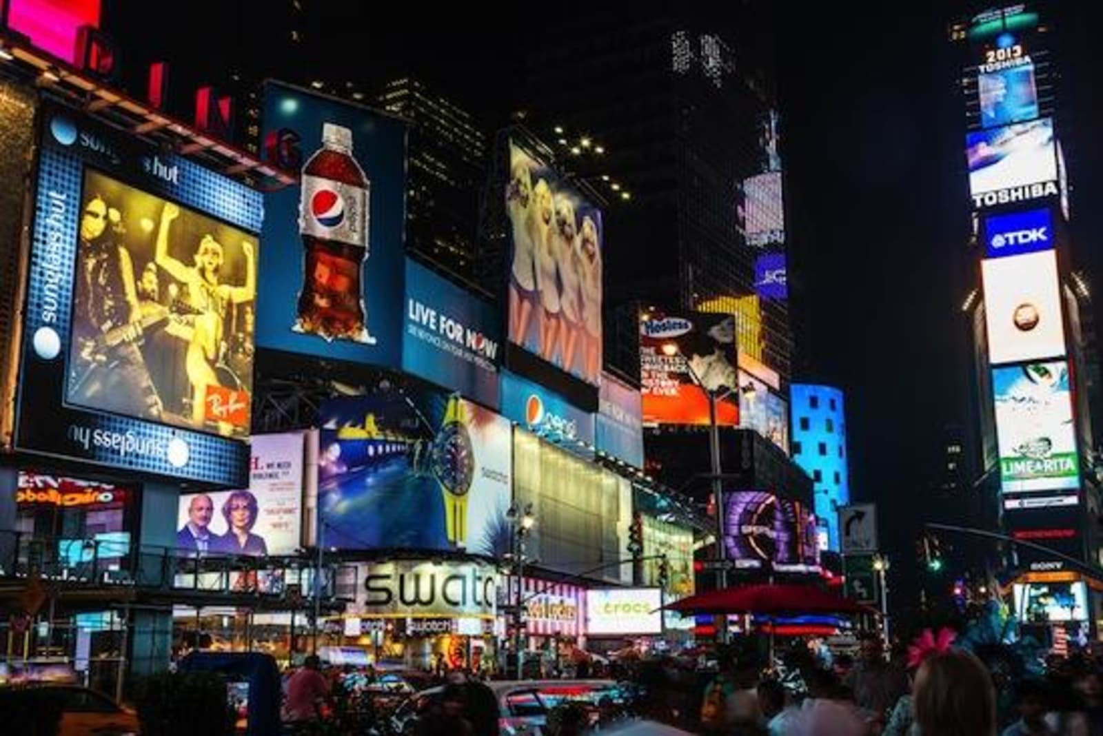 Times Square at night - an assault of neon advertising and screens, with bustling crowds