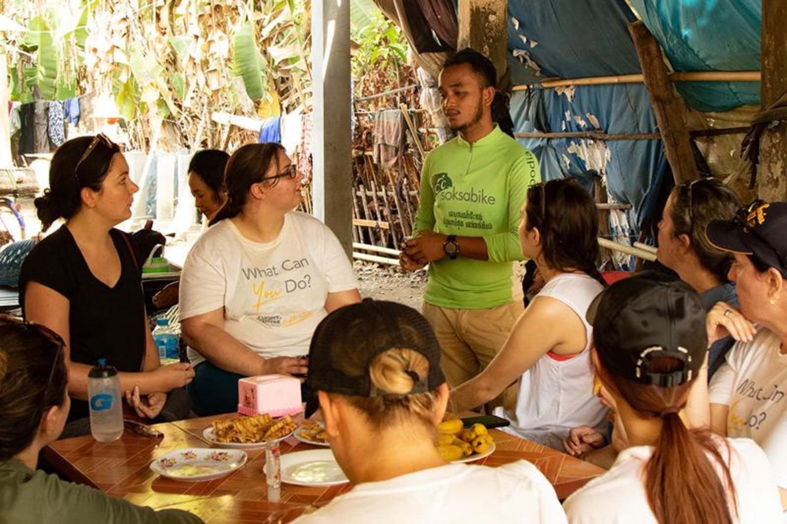 Volunteers sitting at a low table under bamboo and palm tree roofing