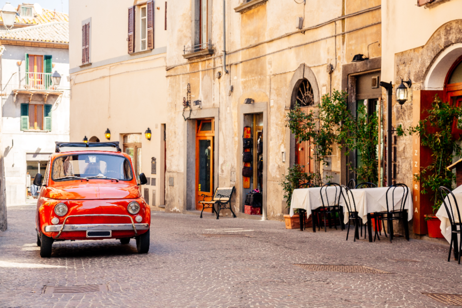 A red vintage Mini Cooper parked on a street in Italy