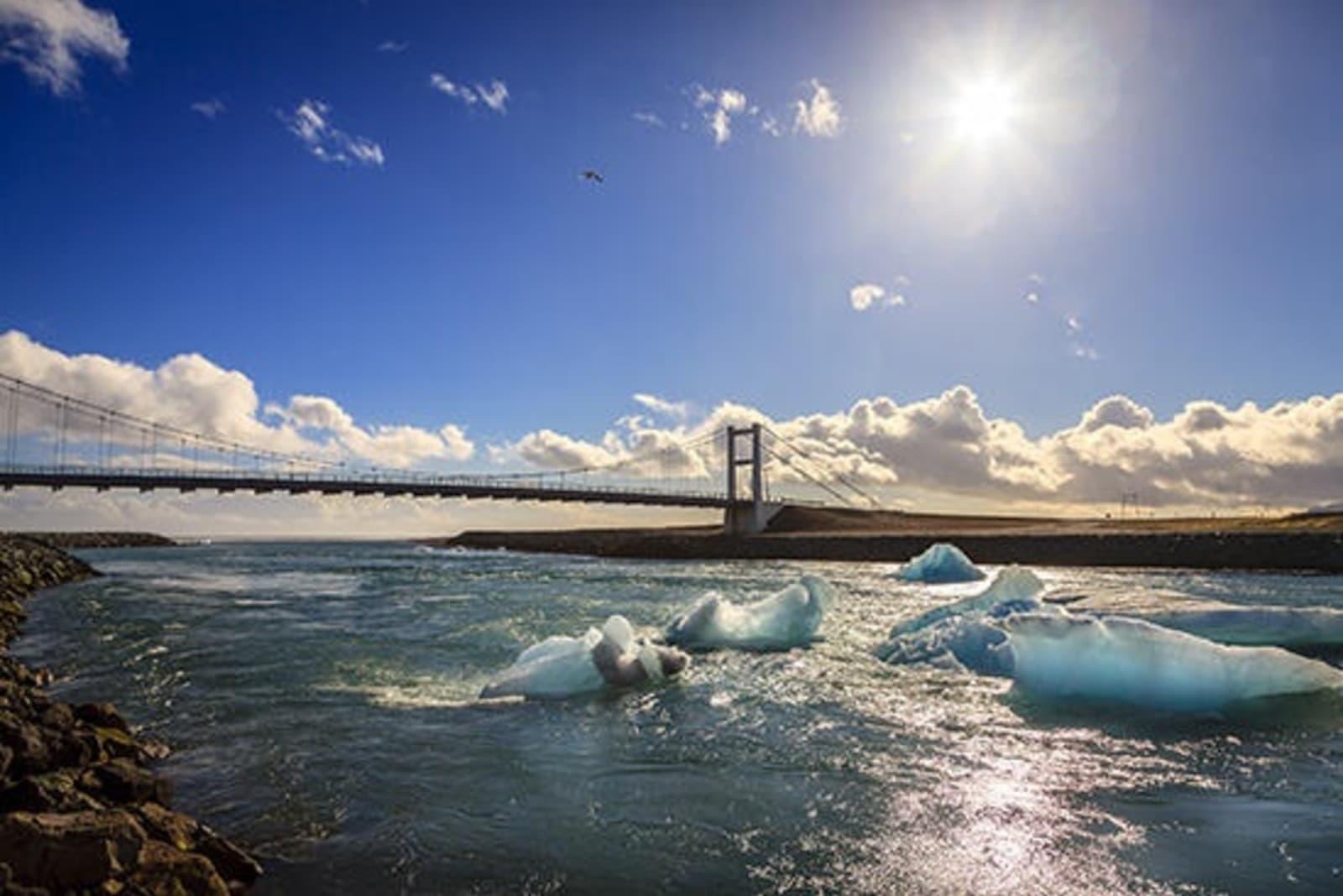 View of a bridge on Jokulsarlton Ring Road with icebergs in the water.