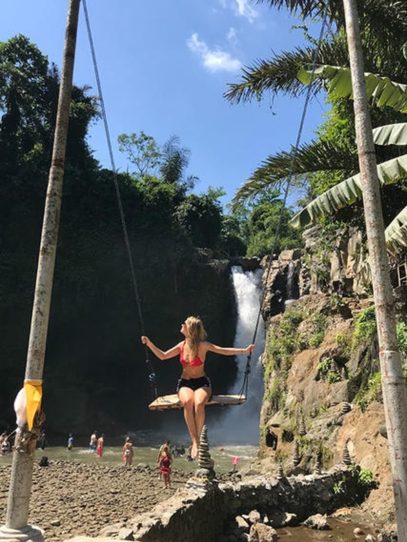 Girl swinging on a big swing in front of a waterfall.