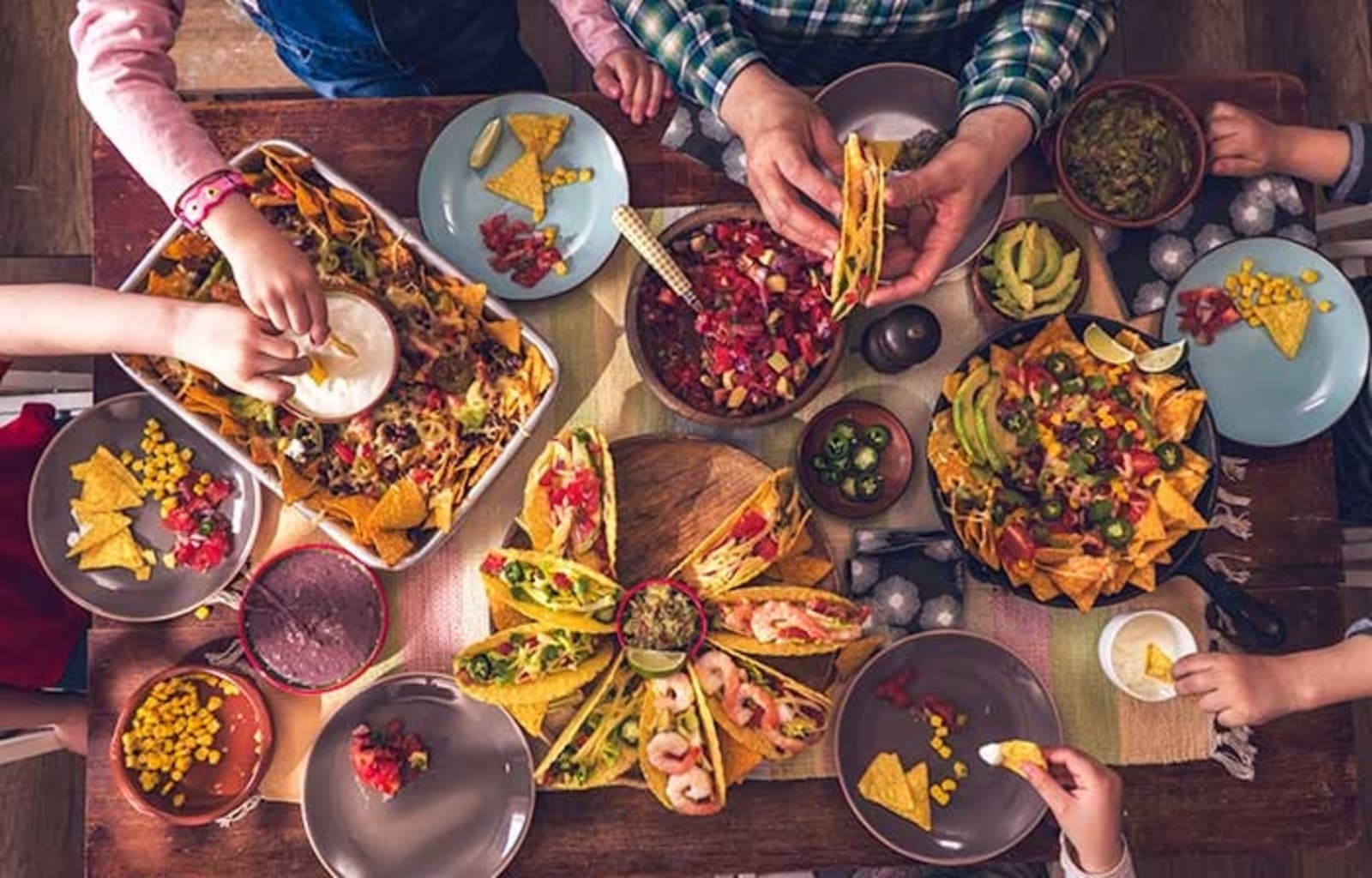 A birds eye view of a family sitting at a table covered in delicious Mexican food