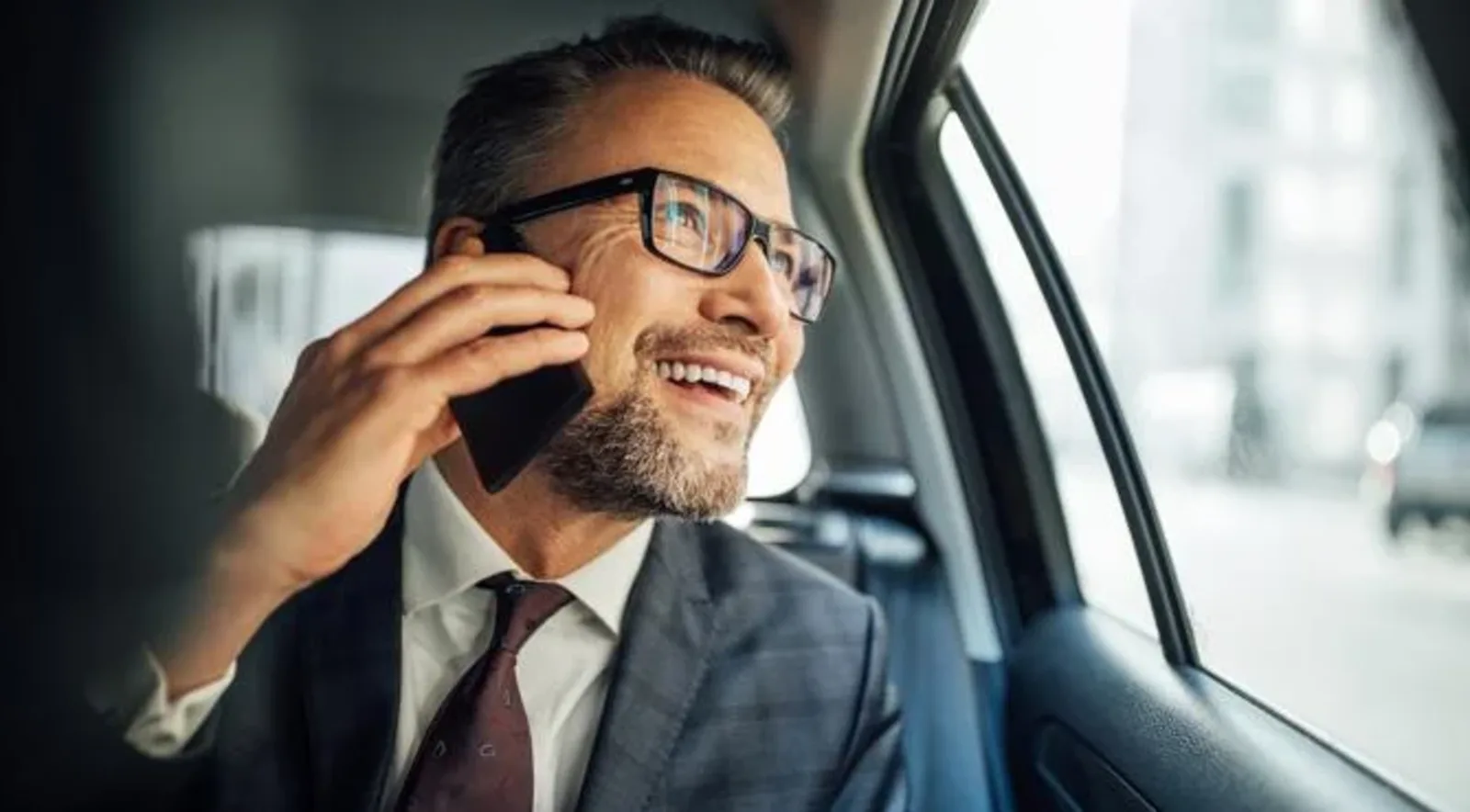 man talking in phone looking outside the window in a car