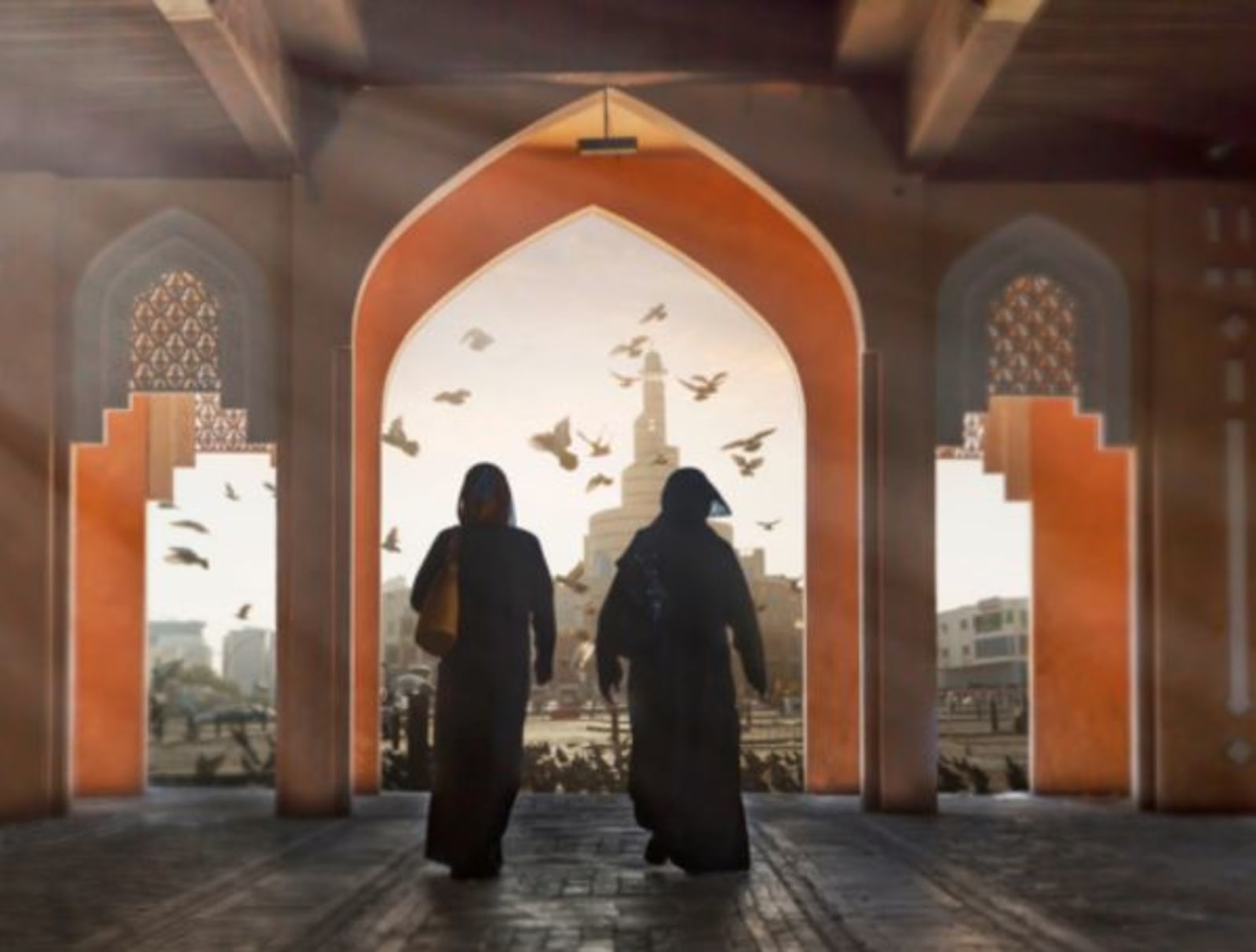 Two Qatari women walk through the entrance to a mosque