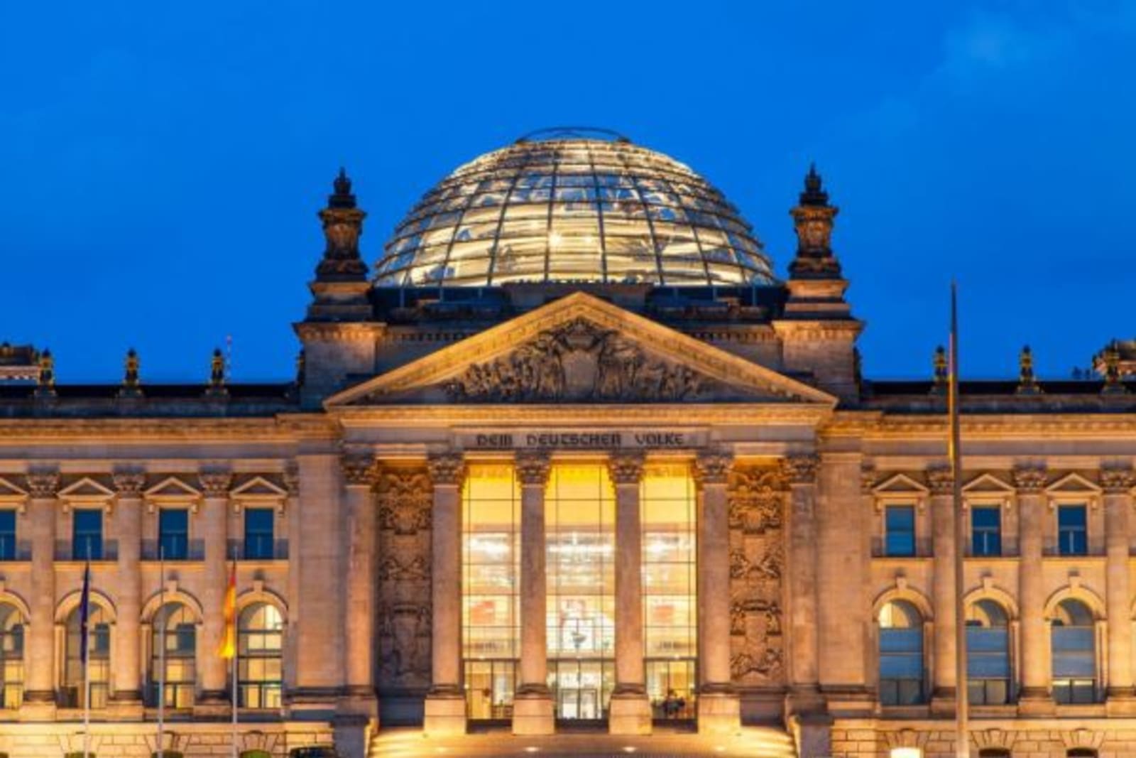 Night shot of the Reichstag, Berlin with lights shining through the entrance windows