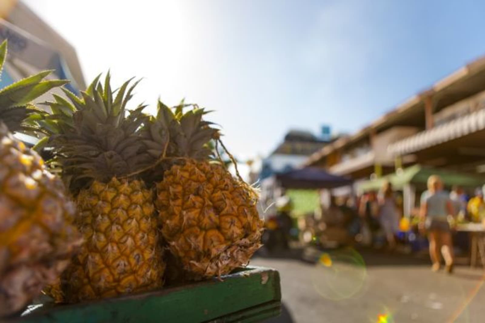 Pineapples in a market with people walking in background blurred