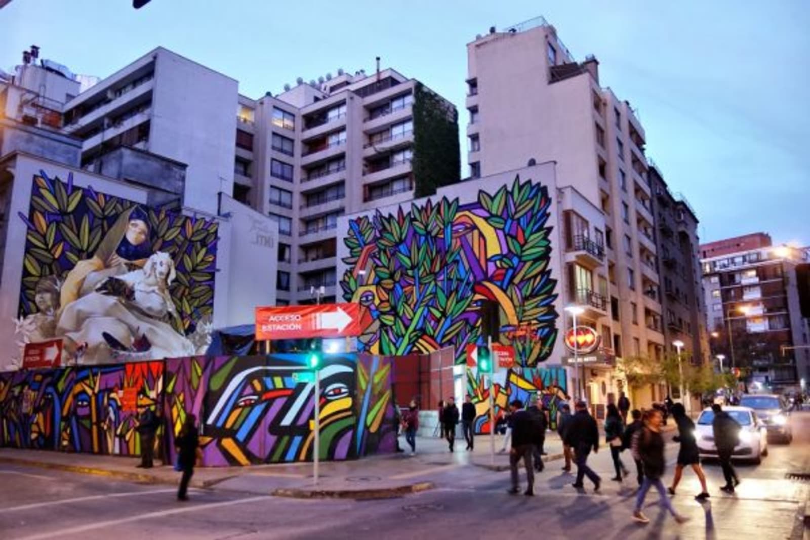 Colourful street art on side of buildings with people walking past