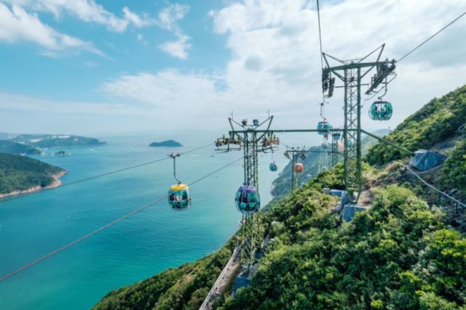 Several colourful cable carts moving with ocean view in Hong Kong