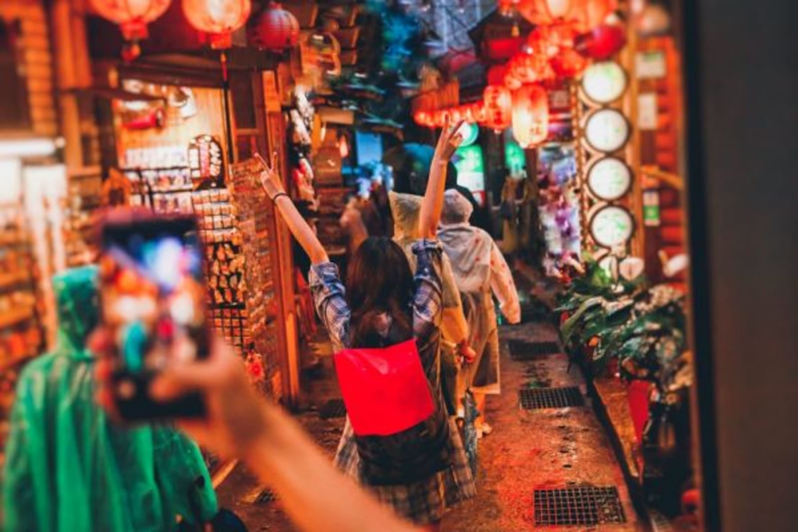 Person taking a photo of a female on their phone in a night market