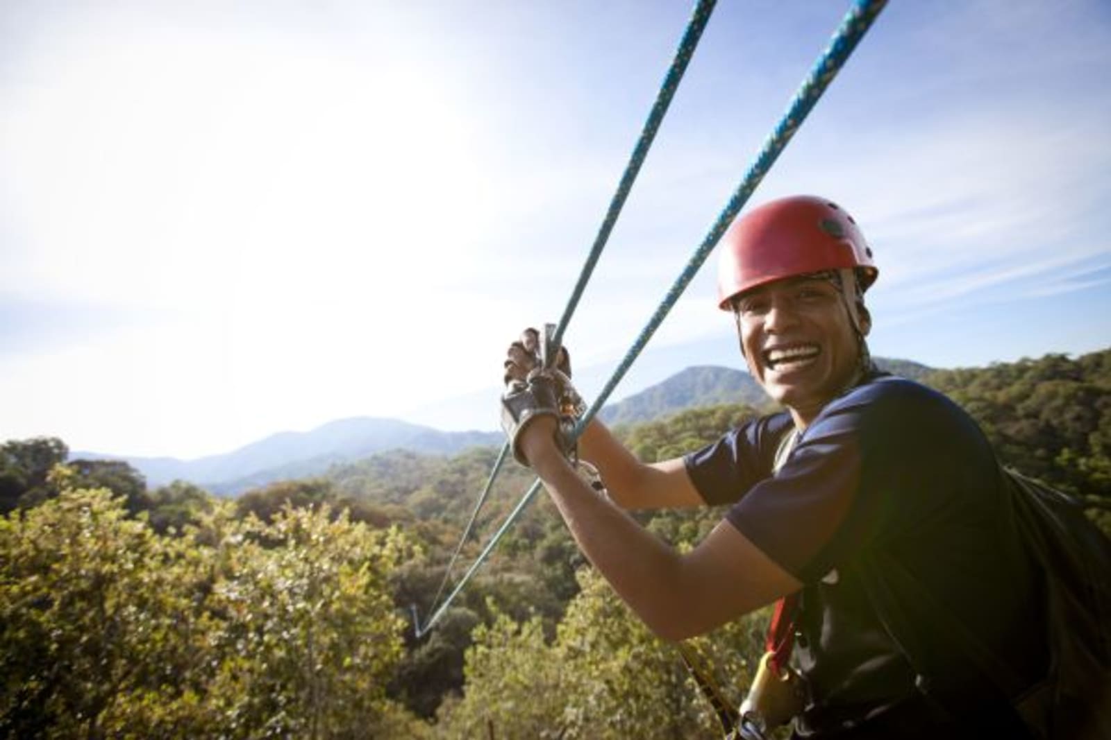 Man smiling looking back attached to a zip line