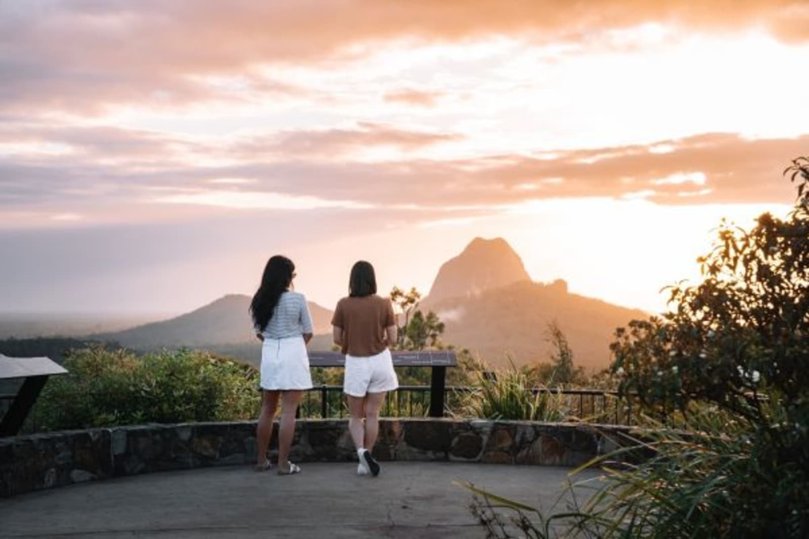 Two females looking at sunset on mountain lookout