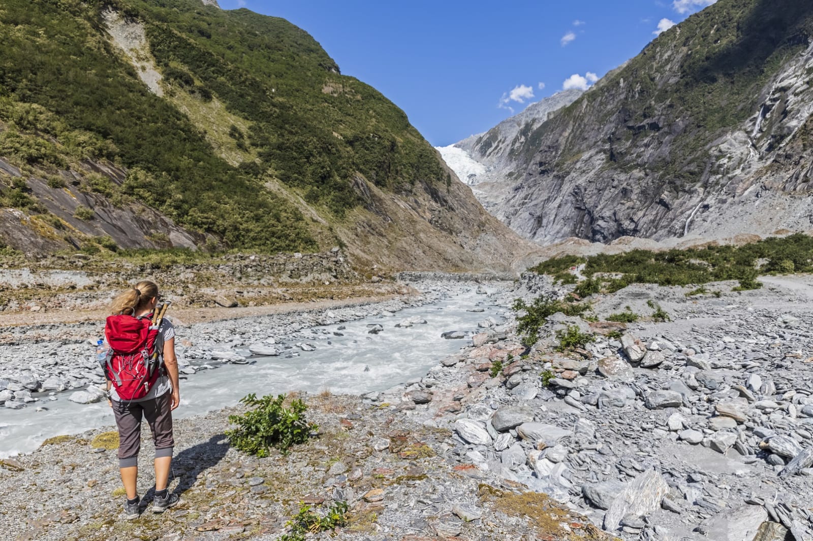 Woman hiking along a shallow stream through mountains