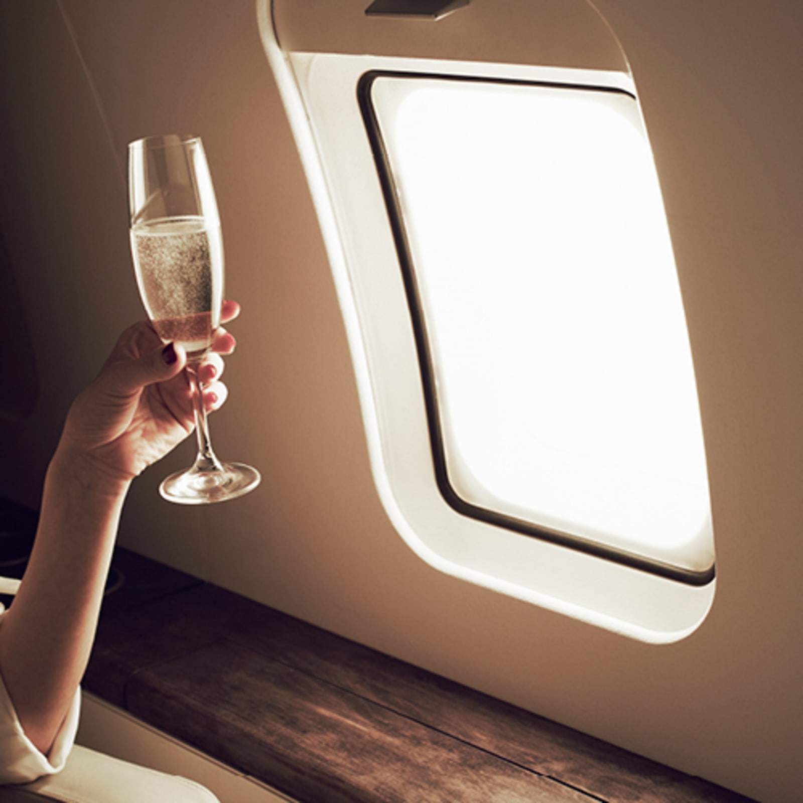 Hand holding fine wine in a business class seat on a flight
