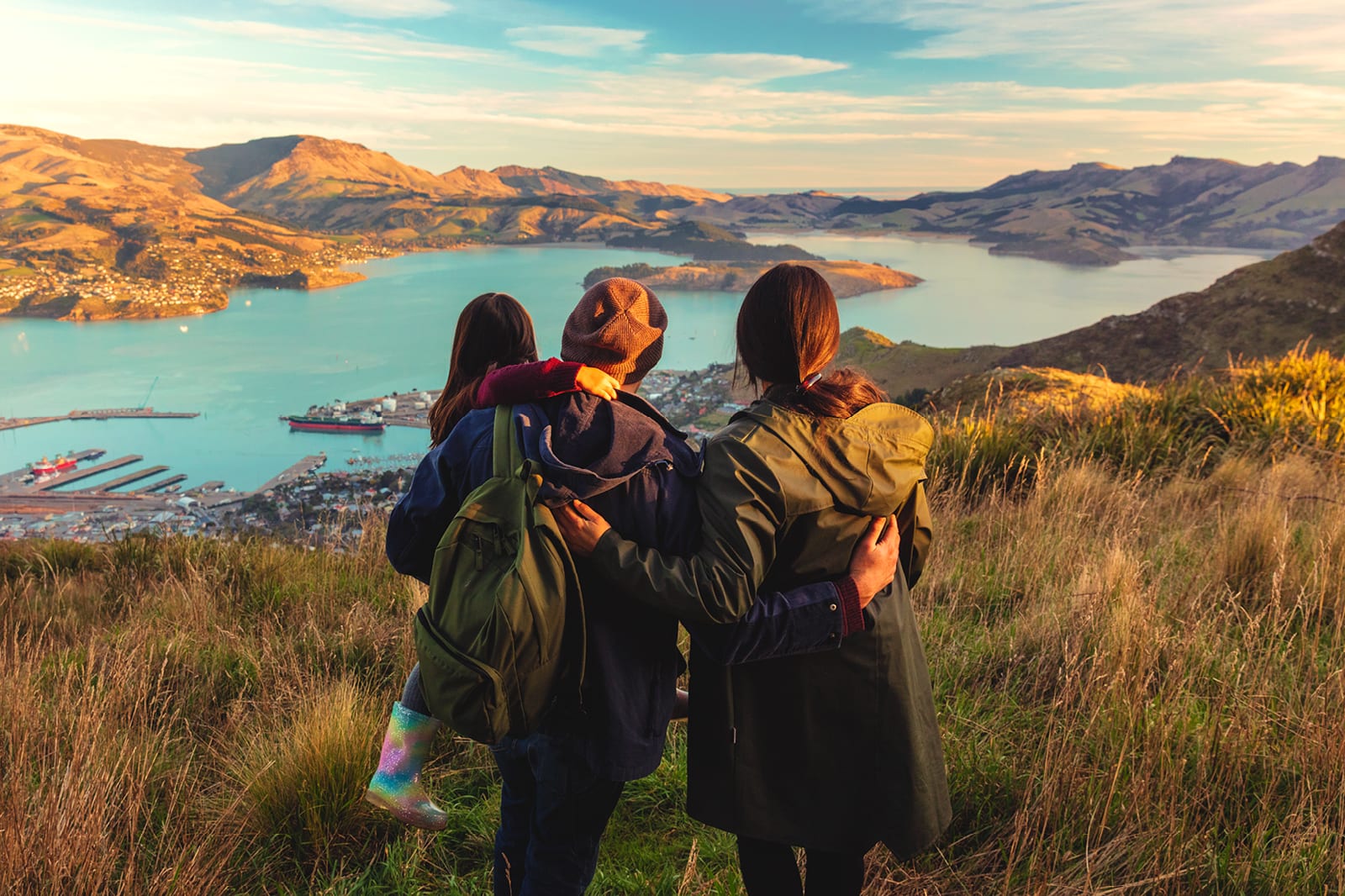 Family of three hikers looking at lakeside towns in New Zealand
