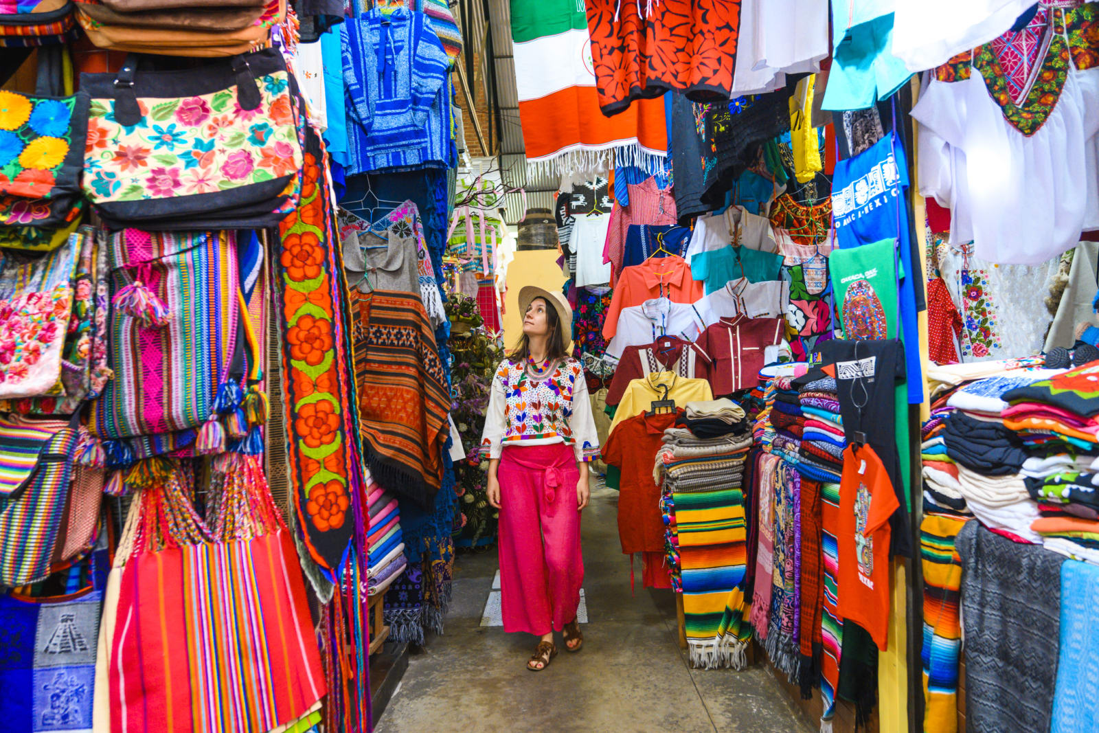 Lady walking through a market with colourful items in mexico