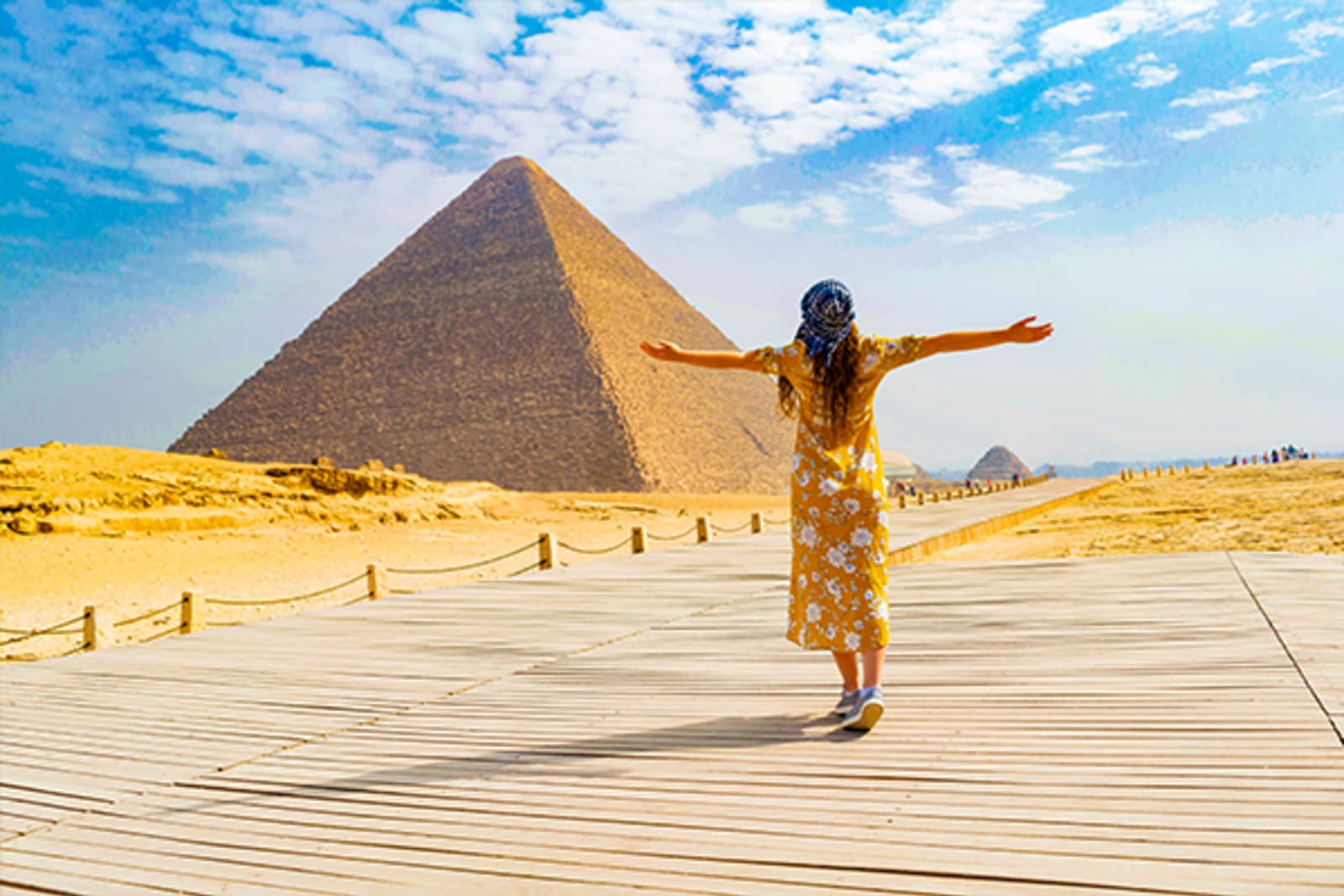 Woman with her arms spread looking at the pyramid of Giza