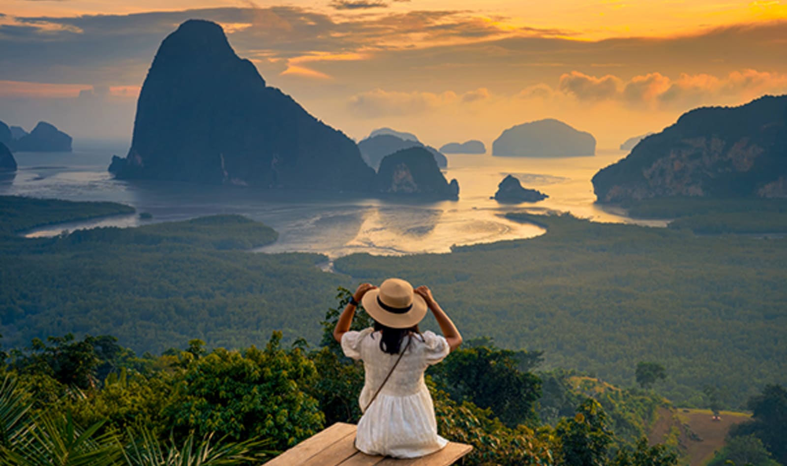 lady sitting on edge of cliff overlooking mountains in phuket