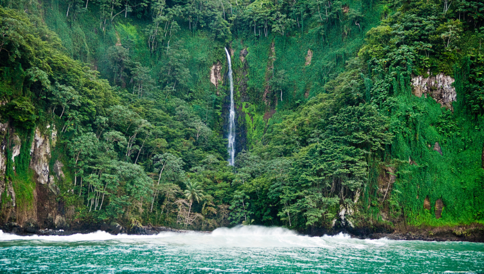 Waterfall on the edge of a cliff leading into the ocean.