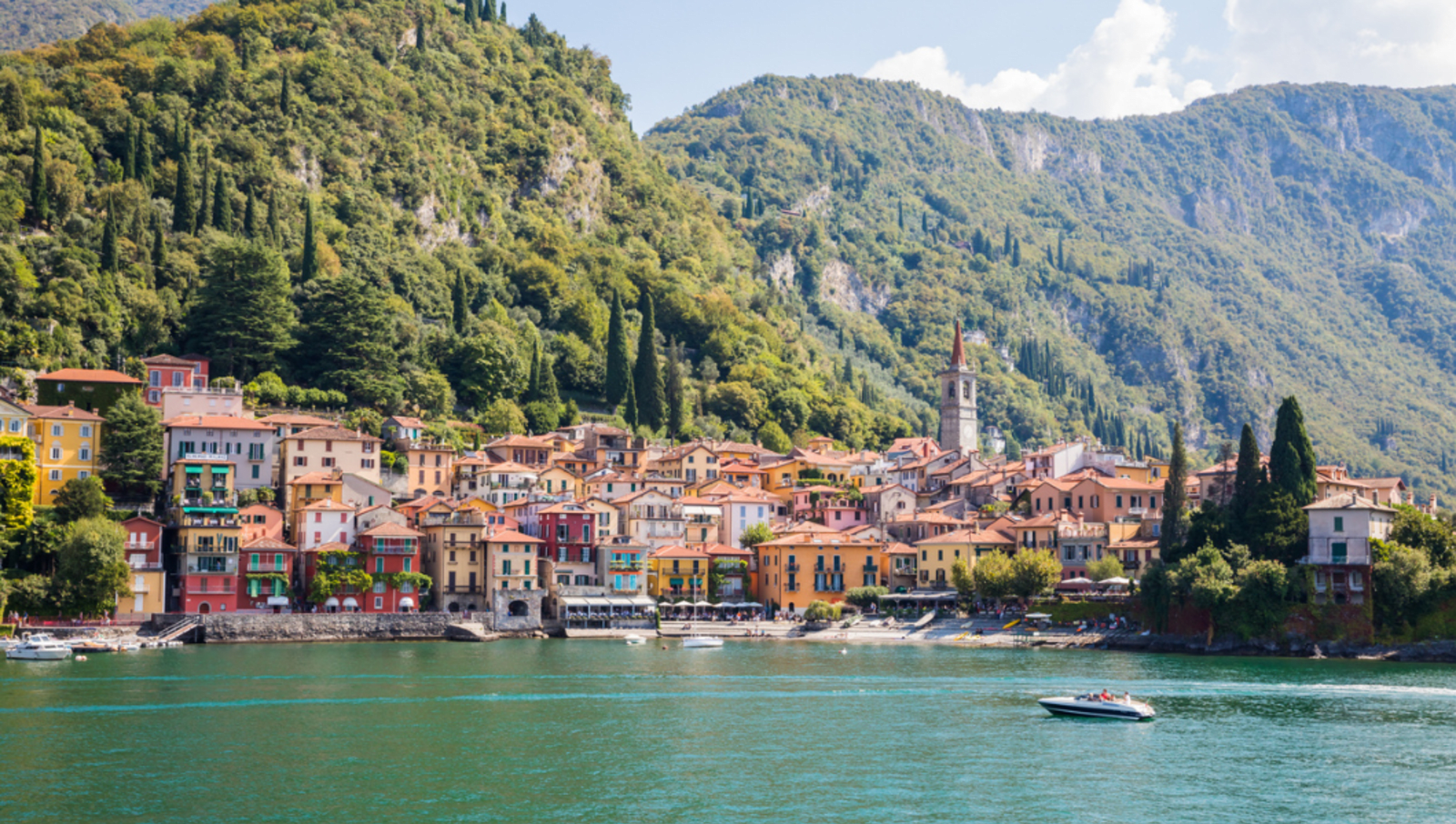 Colourful houses with mountains behind lining the shore of lake como italy